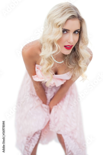 Dreamy blonde model in pink dress posing hands on the thighs