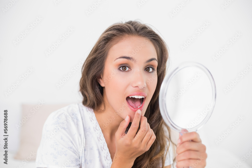 Attractive brunette opening mouth and holding mirror Attractive brunette opening mouth and holding mirror