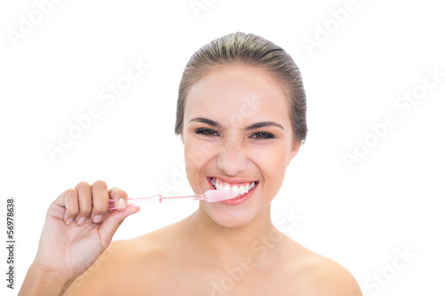 Smiling young brunette woman using a toothbrush