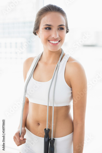 Happy sporty brunette wearing a skipping rope around the neck