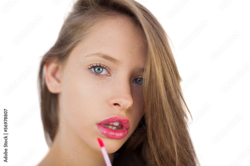 Serious brunette model applying pink gloss on her lips Serious brunette model applying pink gloss on her lips