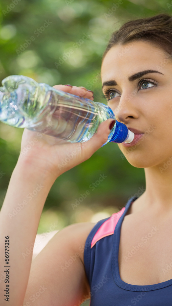 Fit cute woman wearing sportswear drinking from bottle Fit cute woman wearing sportswear drinking from bottle