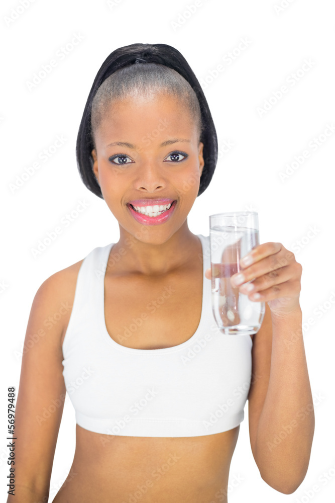 Smiling woman in sportswear holding glass of water while looking Smiling woman in sportswear holding glass of water while looking