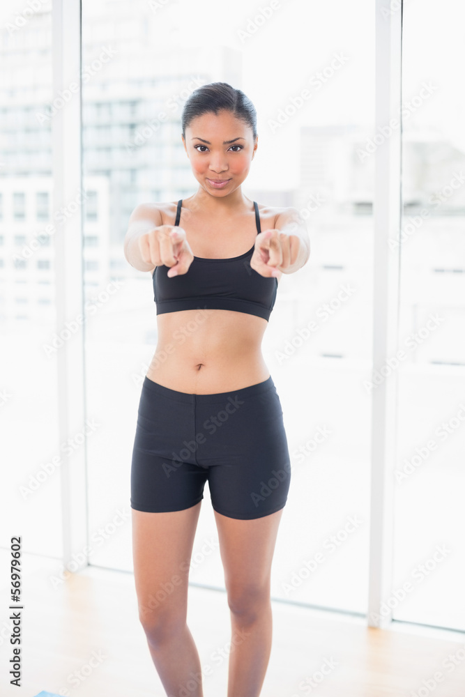 Seductive dark haired model in sportswear pointing her fingers a Seductive dark haired model in sportswear pointing her fingers a