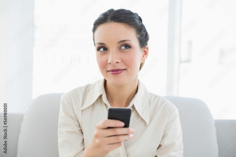 Dreamy stylish brunette businesswoman using her mobile phone Dreamy stylish brunette businesswoman using her mobile phone