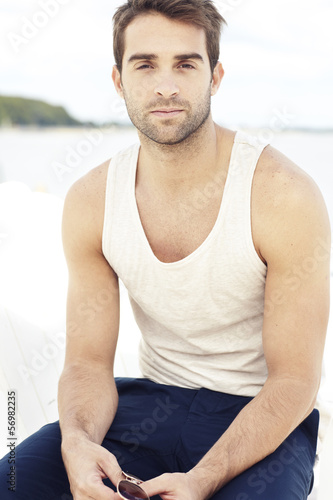Free Download Portrait of mid adult man wearing vest and holding sunglasses - GFXLoad