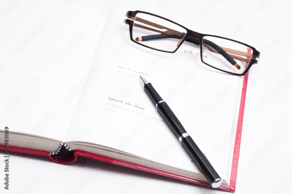 Closeup of reading glasses on the book with pen Closeup of reading glasses on the book with pen