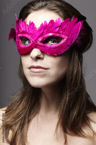 Young beautiful girl with a pink mask on grey background