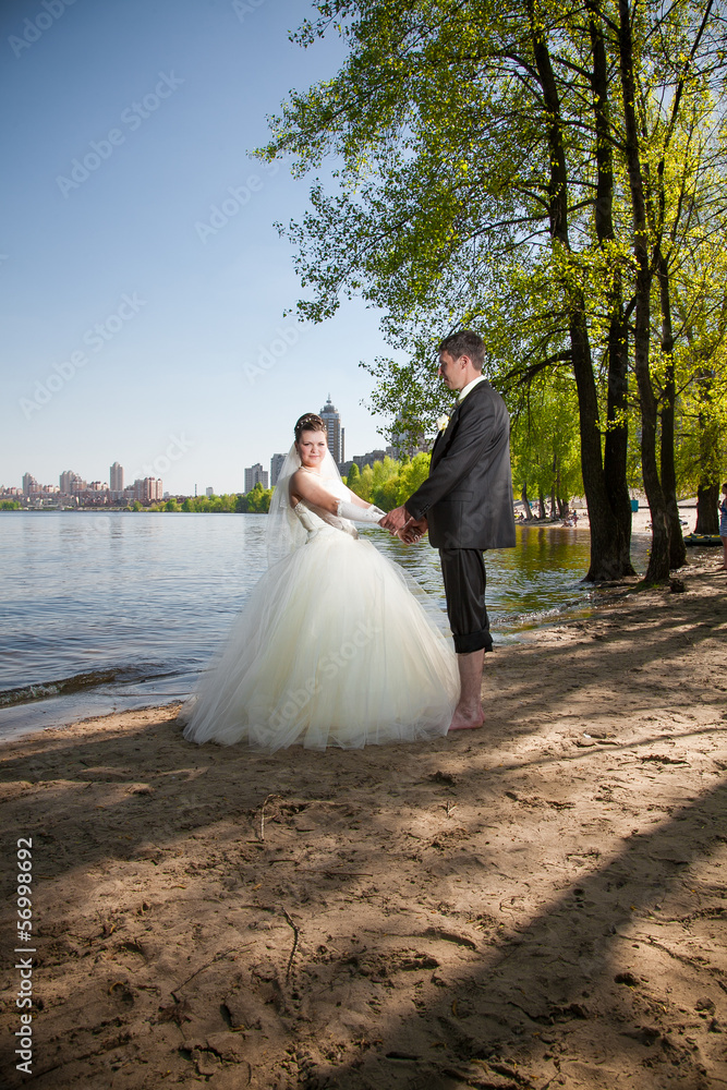Beatiful newly married couple walking on beach near river Beatiful newly married couple walking on beach near river