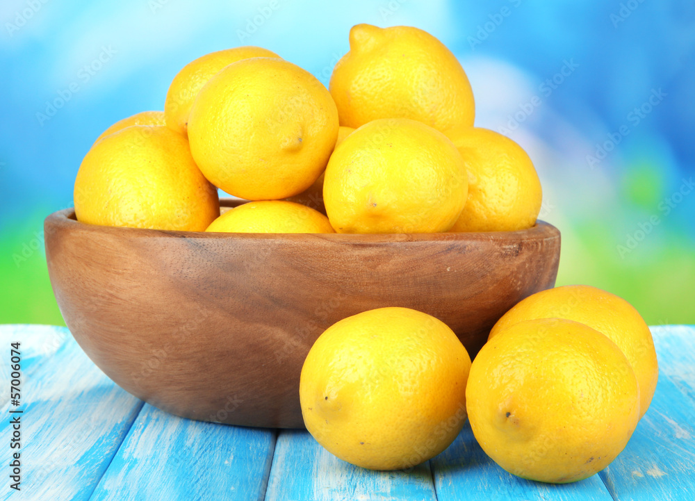 Ripe lemons in bowl on table on bright background