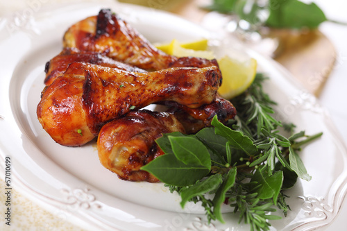 Roast chicken legs with lemon and herbs on plate.