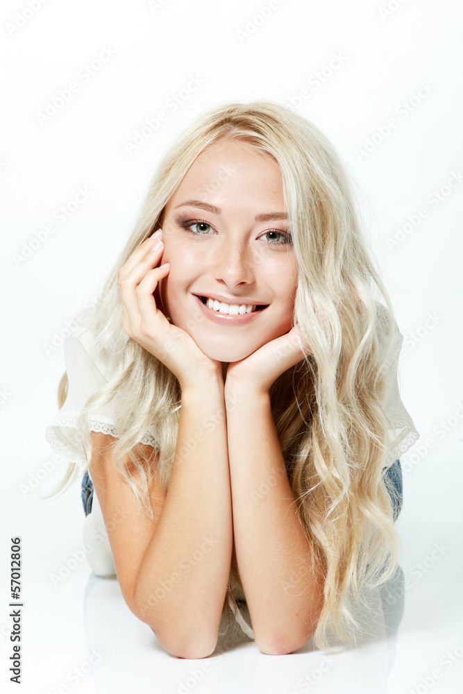 Fototapeta premium Beautiful blond teen girl lying, looking at camera and happy smi