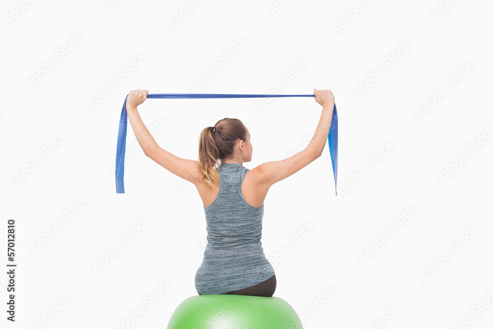Blonde woman sitting on a fitness ball training with a resistanc Blonde woman sitting on a fitness ball training with a resistanc