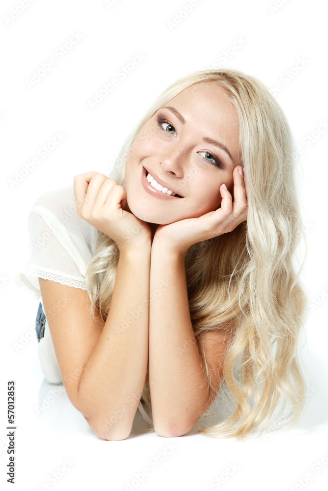 Beautiful blond teen girl lying, looking at camera and happy smi