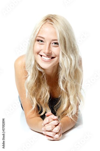 Beautiful blond teen girl lying, looking at camera and happy smi photo