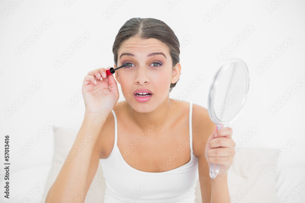 Surprised young brown haired model in white pajamas applying mas Surprised young brown haired model in white pajamas applying mas