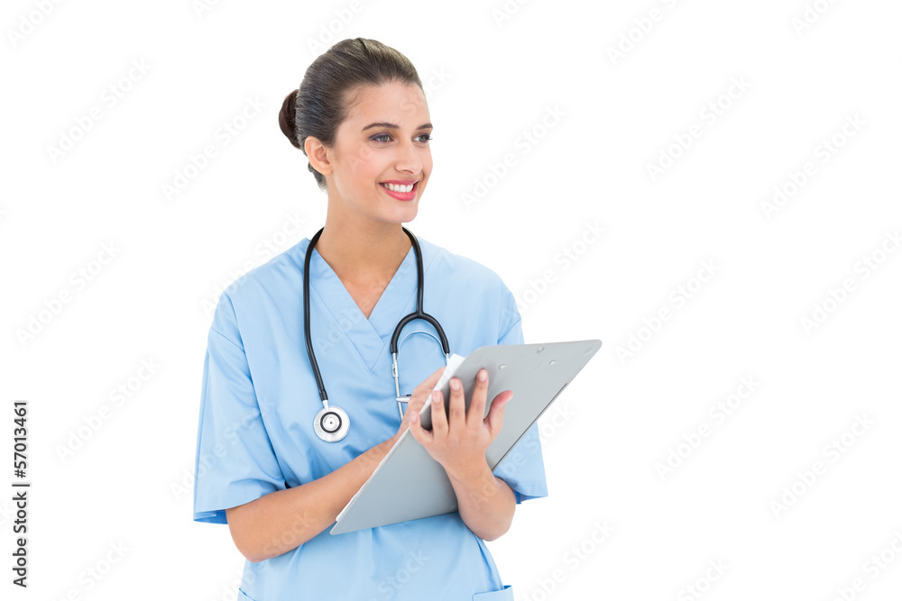 Attractive brown haired nurse in blue scrubs checking a report Attractive brown haired nurse in blue scrubs checking a report