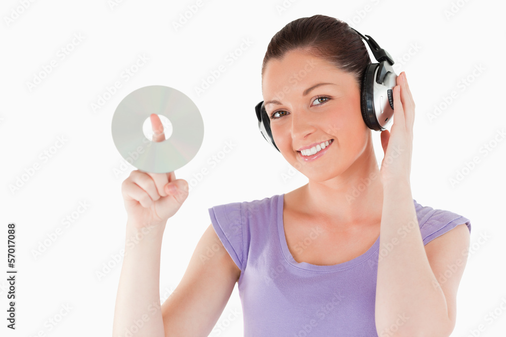 Cute woman with headphones holding a CD while standing Cute woman with headphones holding a CD while standing