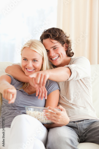 Portrait of a couple watching TV while eating popcorn