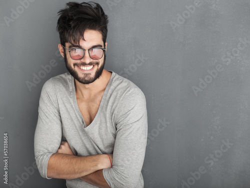 sexy fashion man with beard dressed casual smiling against wall