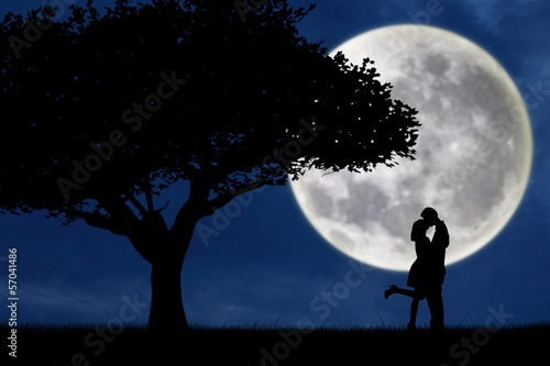 Couple kissing by a tree on blue full moon silhouette