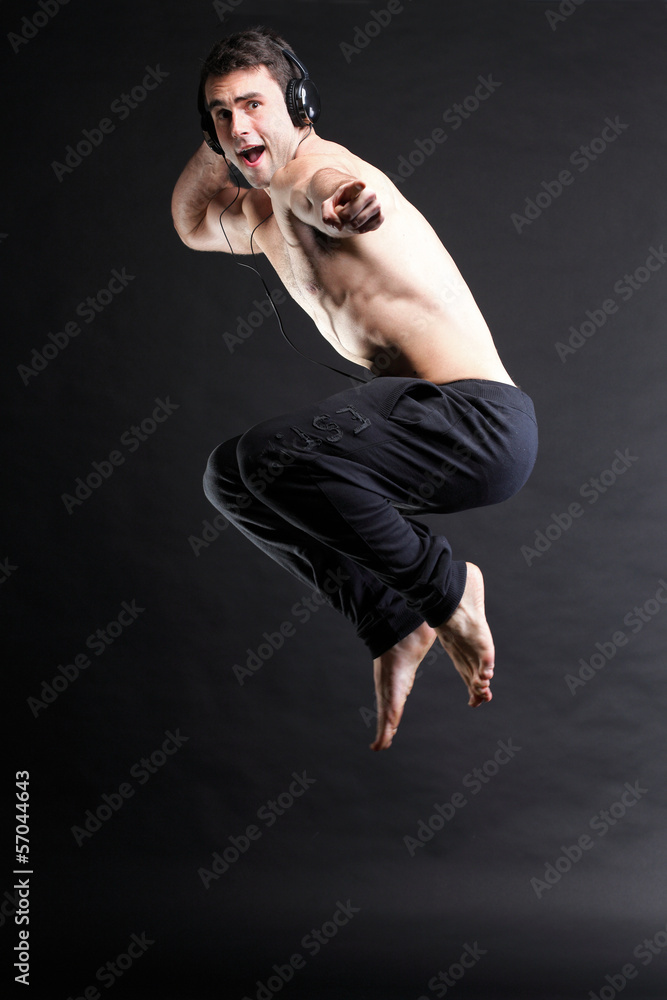 Young man jumping and listening music isolated gray background