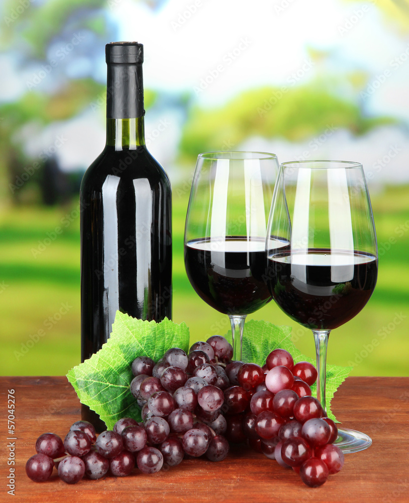 Obraz premium Ripe grapes, bottle and glasses of wine on bright background