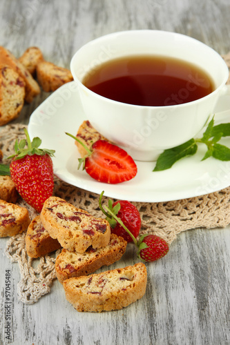 Cup of tea with cookies and strawberries on table close-up