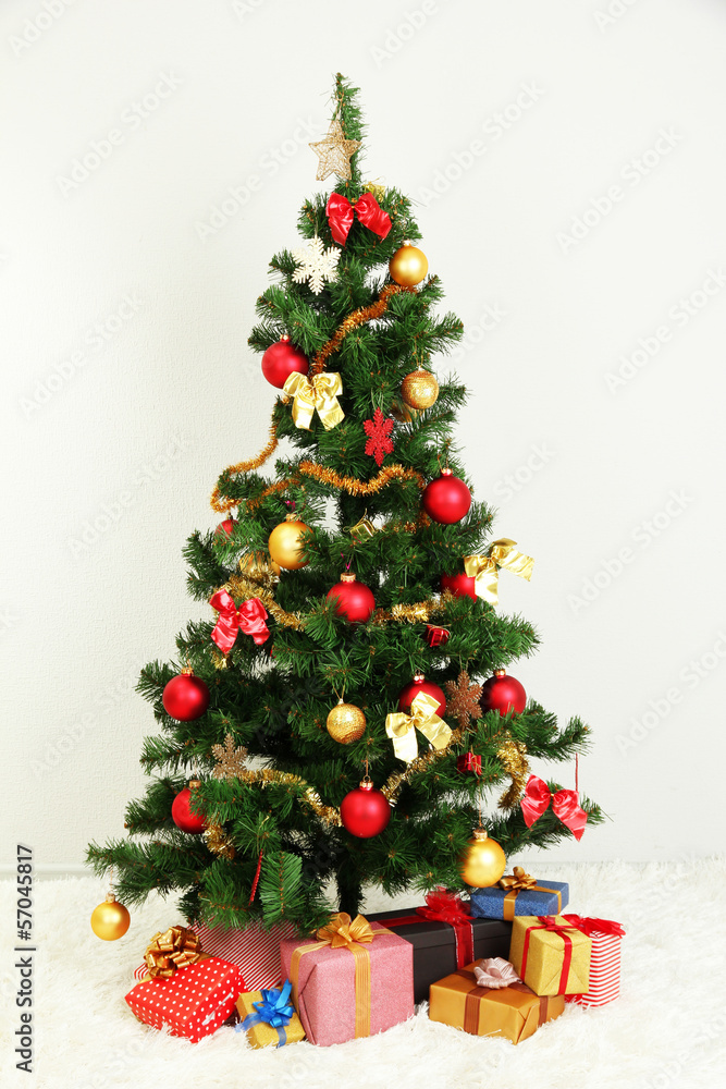 Decorated Christmas tree with gifts on grey wall background Decorated Christmas tree with gifts on grey wall background