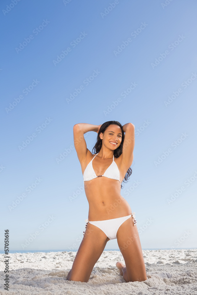 Smiling attractive woman in white bikini posing