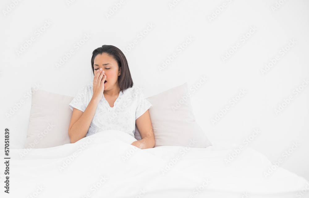 Exhausted young dark haired model yawning lying in her bed Exhausted young dark haired model yawning lying in her bed