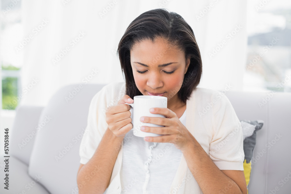 Peaceful young dark haired woman in white clothes enjoying coffe