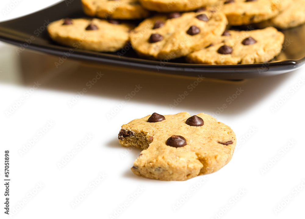 Chocolate chip cookie with a bite and pile of cookies in a plate