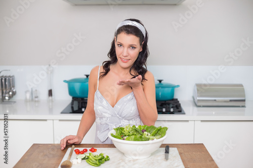 Peaceful pretty brunette preparing healthy salad blowing kiss