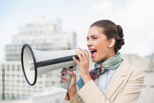 Angry smart brown haired businesswoman screaming in a megaphone
