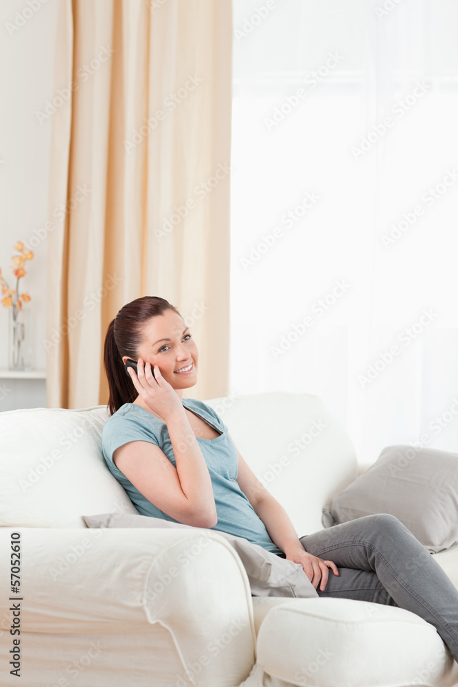 Charming woman on the phone while sitting on a sofa Charming woman on the phone while sitting on a sofa