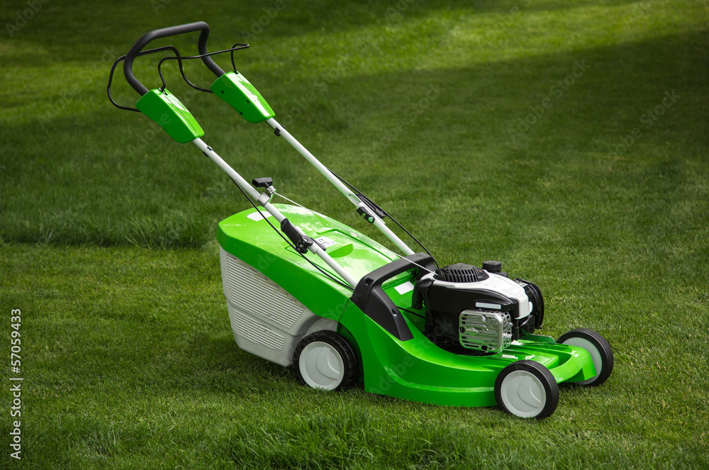Fototapeta premium Green lawnmower on green lawn