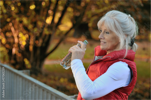 Sportliche Seniorin erfrischt sich mit Mineralwasser