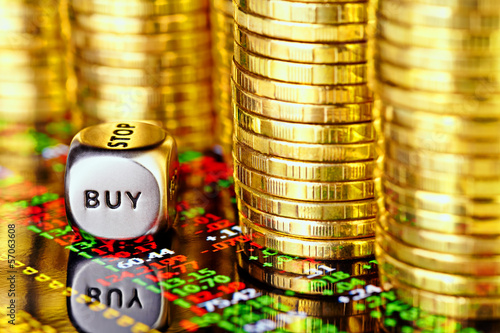 Golden coins, financial chart and dices cube with the word BUY.