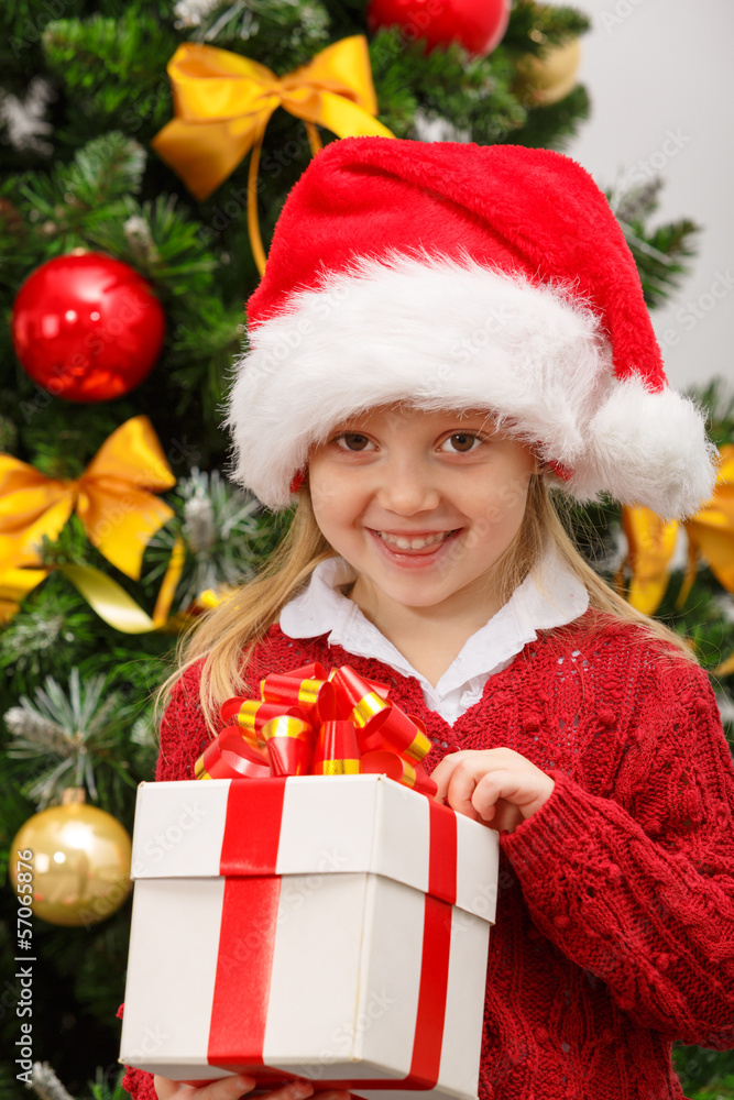 Happy little girl with gift box near the Christmas tree Happy little girl with gift box near the Christmas tree