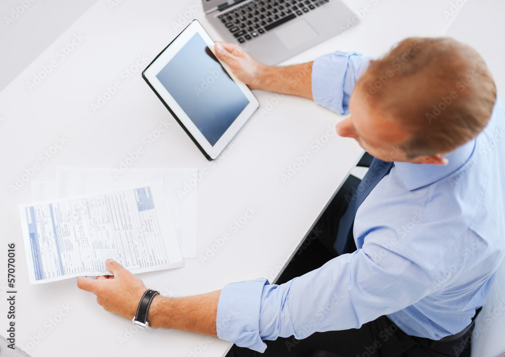 businessman with tablet pc and papers in office