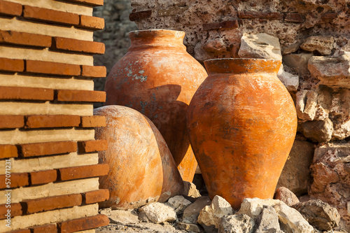 Terracotta, a clay amphora in garden, bricks wall in front.