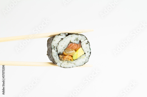 Single sushi roll in chopsticks on white background