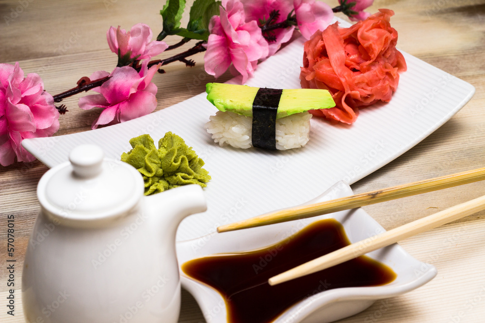 Avocado sushi nogoro in chopsticks with soy sauce Avocado sushi nogoro in chopsticks with soy sauce