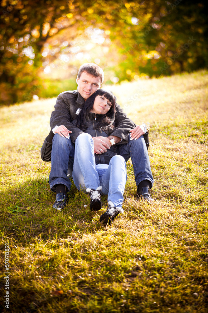 Fototapeta premium Couple in love sitting on hill on sunset
