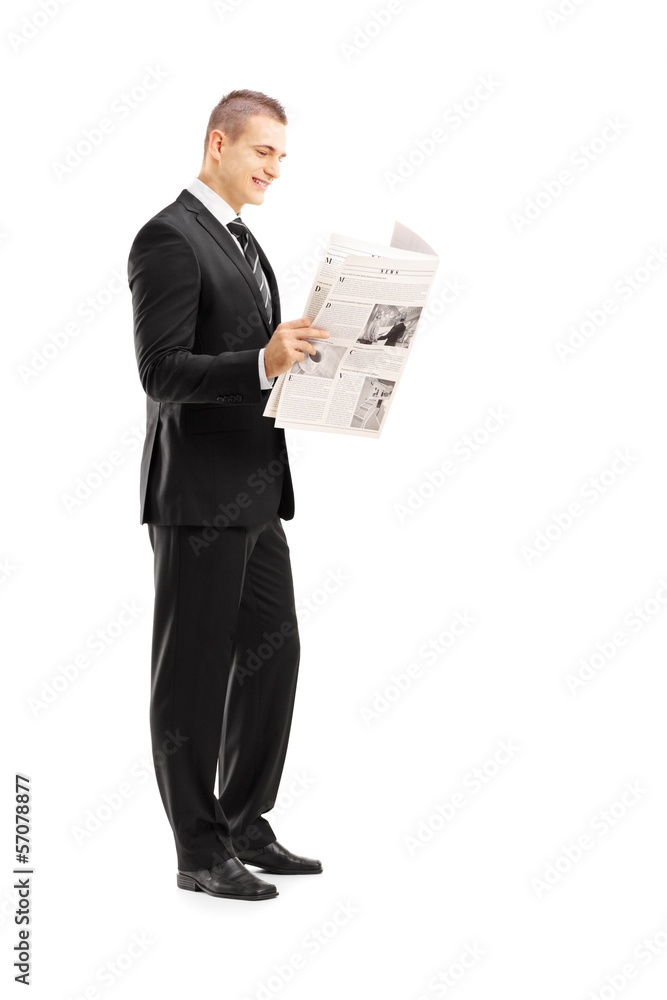 Full length portrait of a young businessman reading a newspaper Full length portrait of a young businessman reading a newspaper