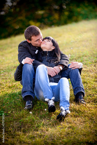 Beautiful couple sitting on grass and kissing