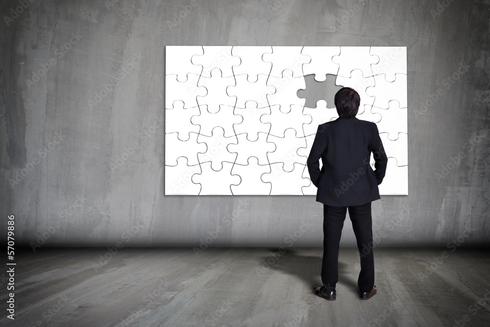 Businessman figuring out puzzle pieces with piece missing on gre Businessman figuring out puzzle pieces with piece missing on gre