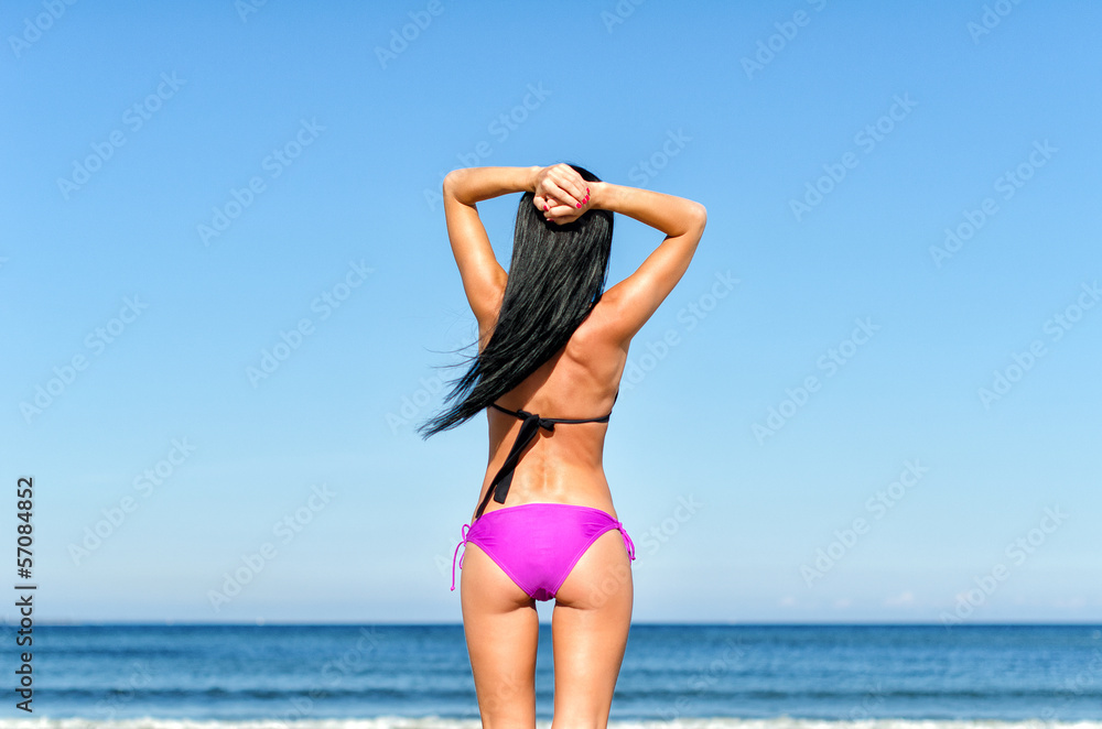 Young woman sunbathes at the beach. From the back. Young woman sunbathes at the beach. From the back.