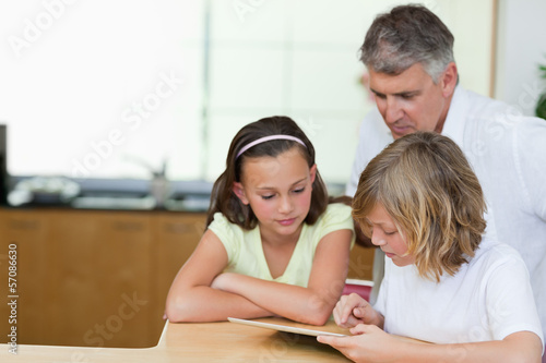 Father together with children and tablet in the kitchen
